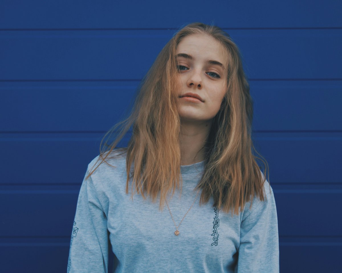 Retrato de una adolescente con expresión seria contra un fondo azul