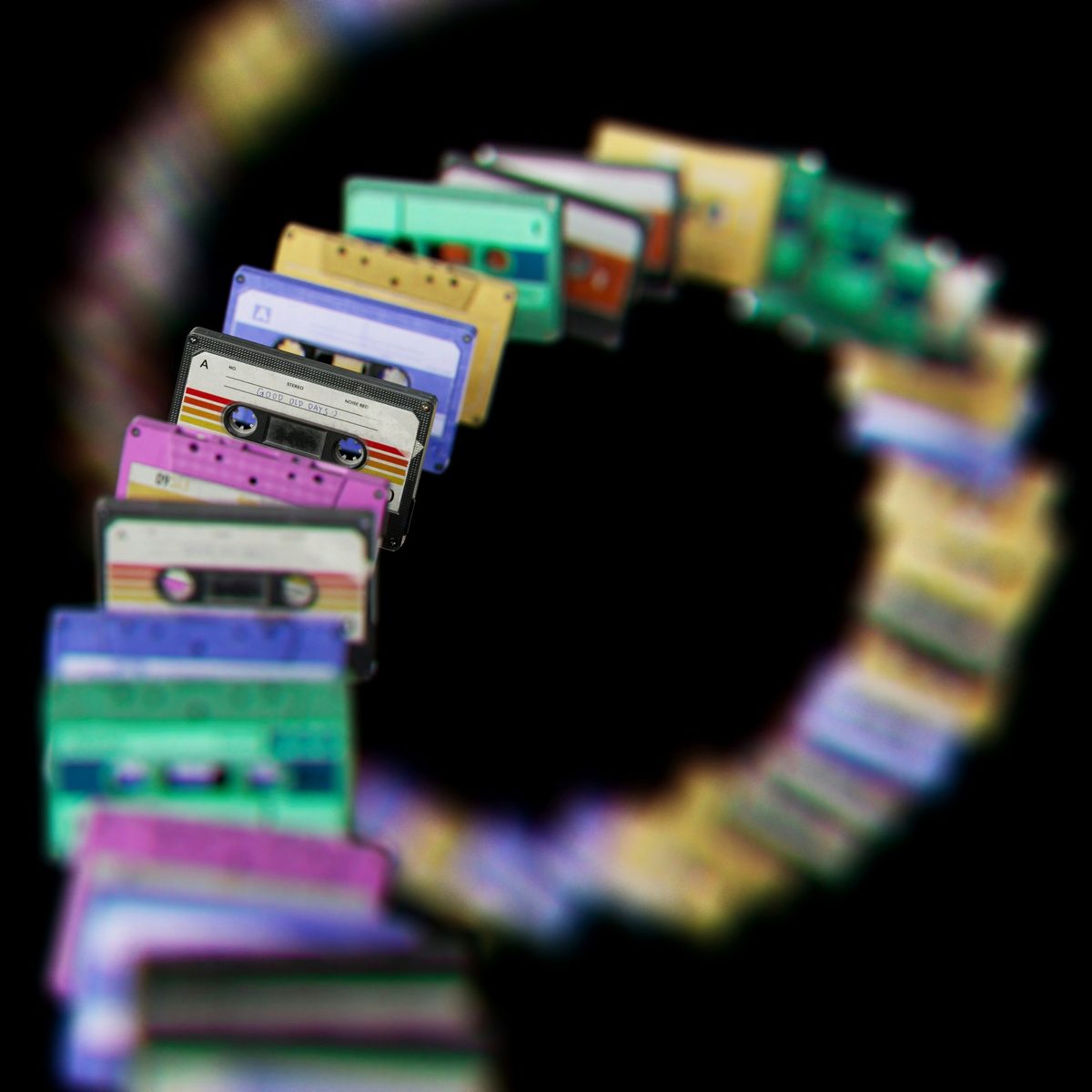 Hilera de casetes de colores dispuestos en espiral sobre fondo negro, con uno enfocado que dice "Good old days"