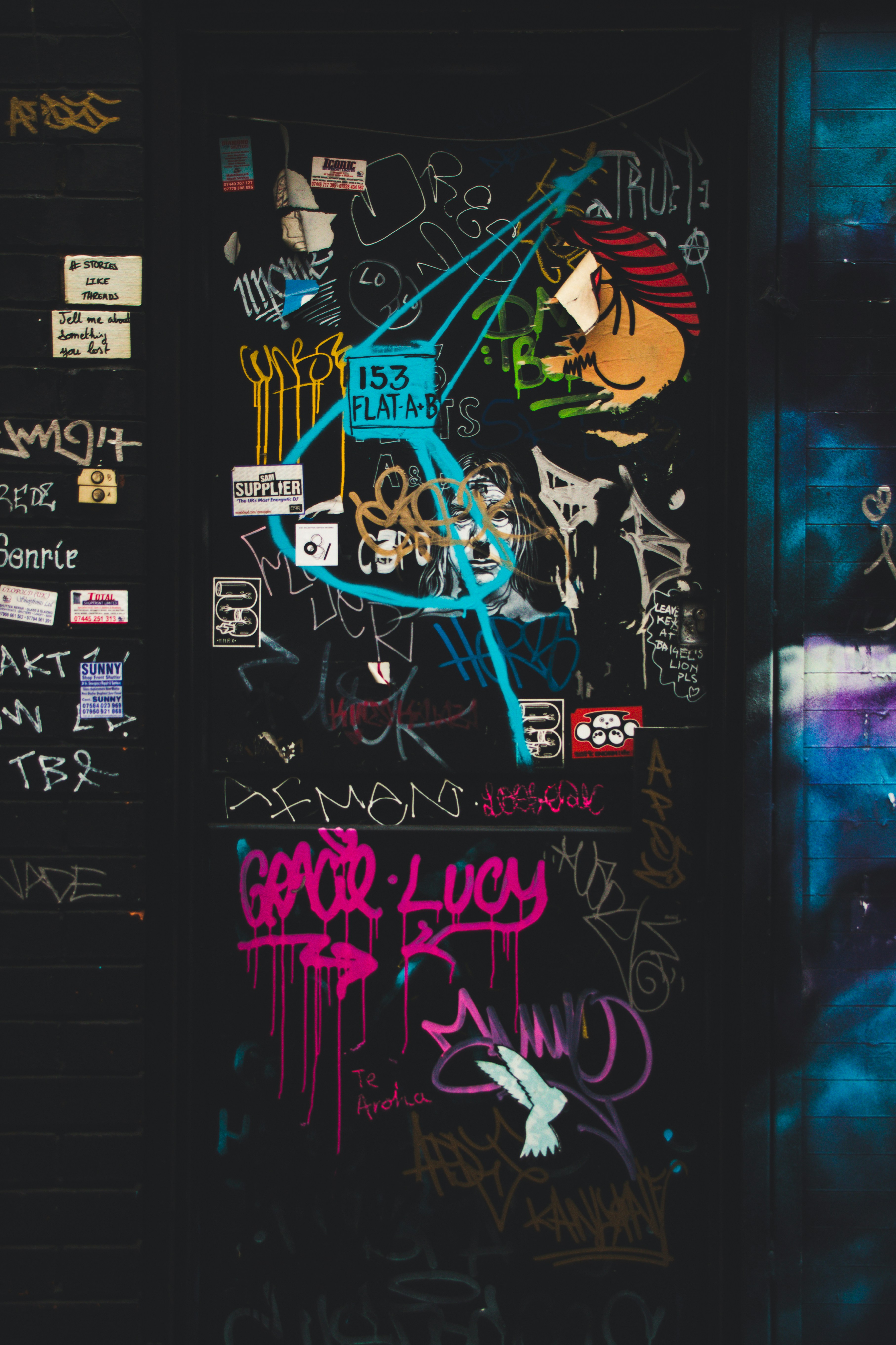 Muro cubierto de grafitis, stickers y mensajes superpuestos en distintos colores