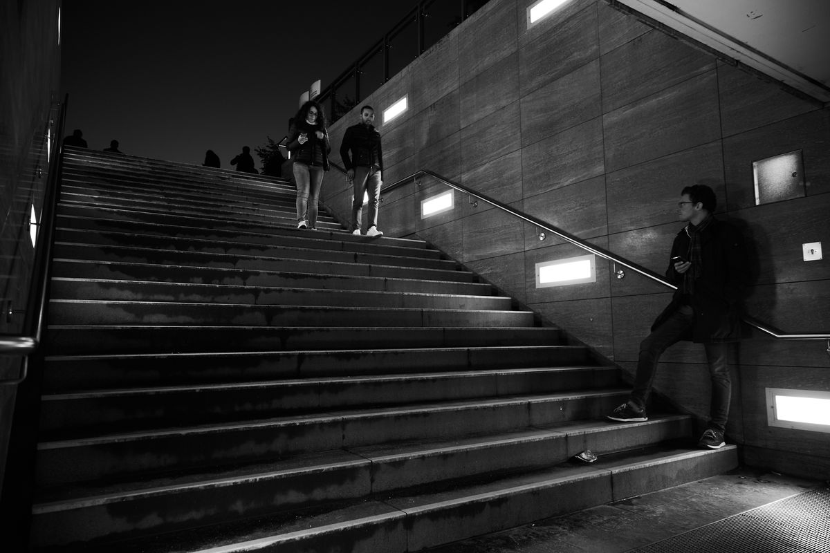 Fotografía en blanco y negro de personas bajando una escalera de hormigón por la noche