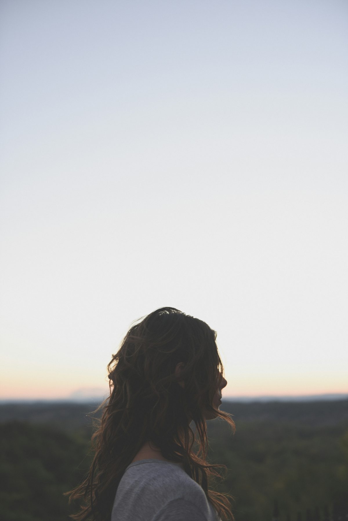 Mujer de espaldas mirando el horizonte al atardecer