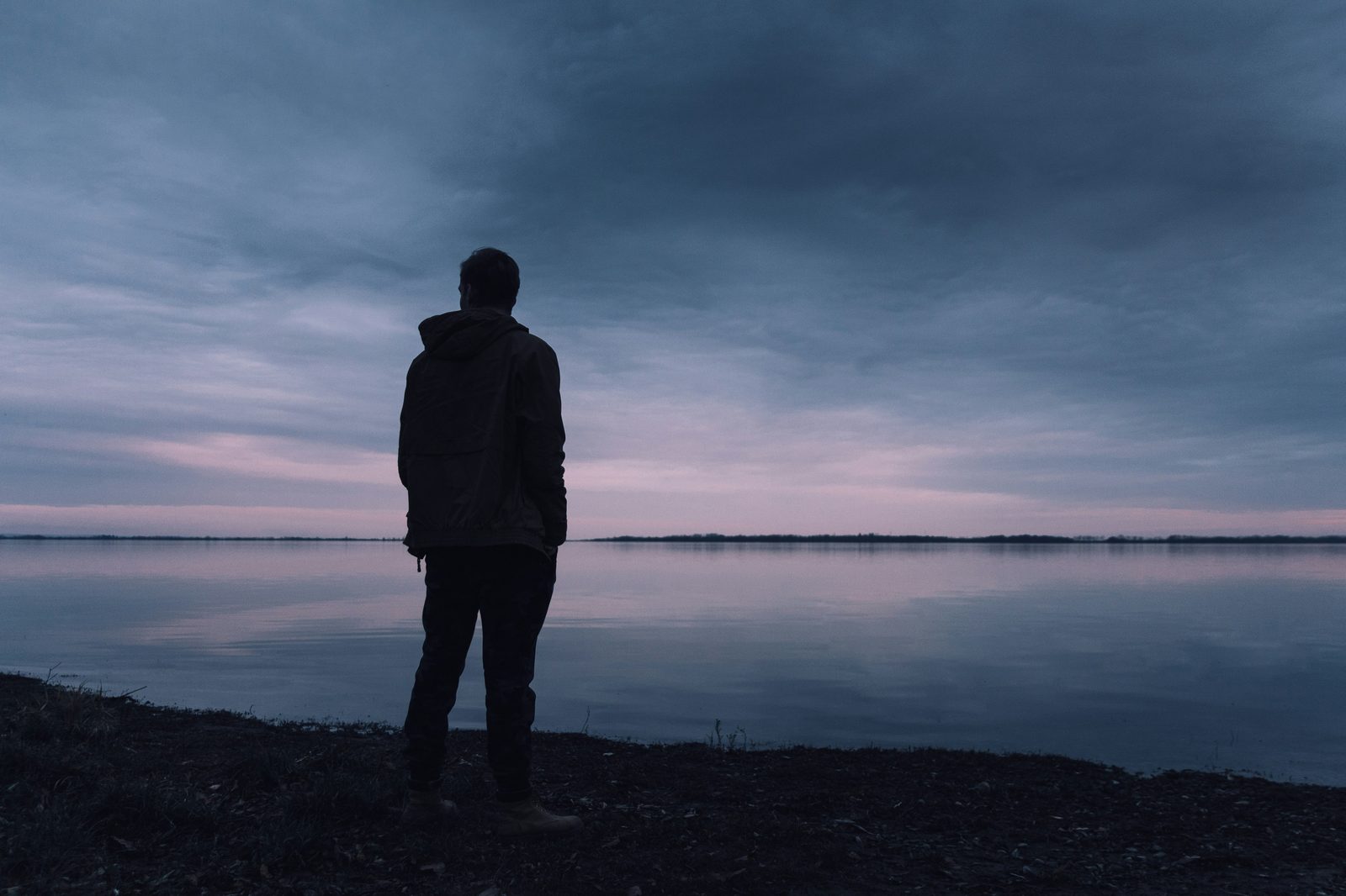 Silueta de un hombre solo frente a un lago