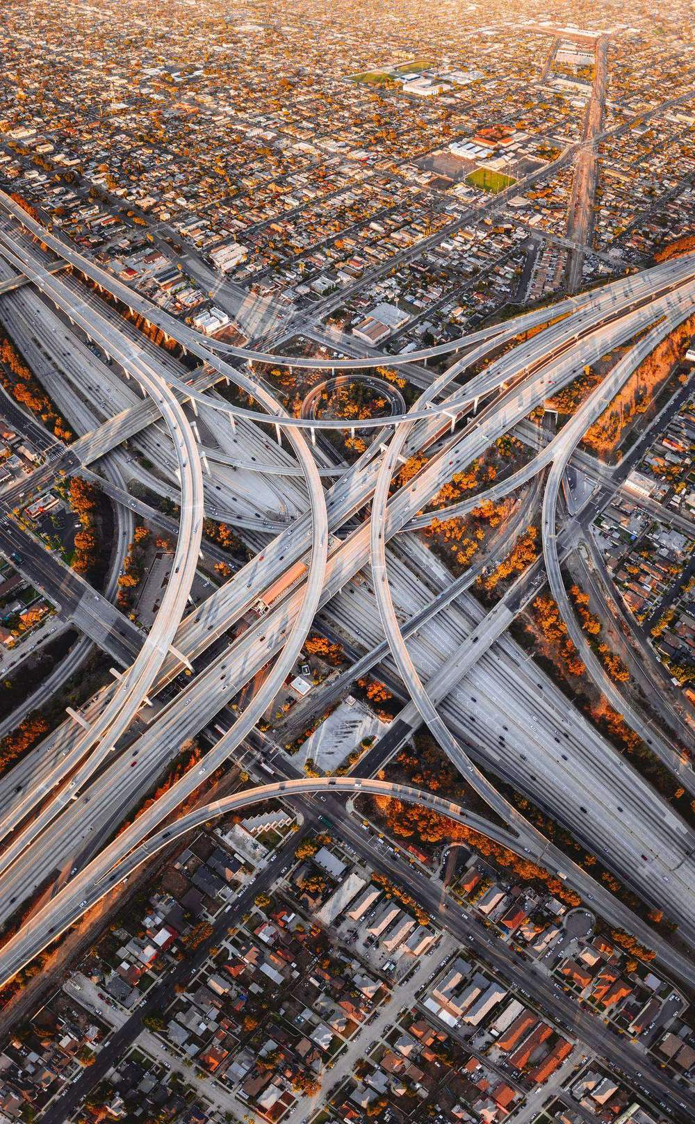 Vista aérea de un complejo nudo de autopistas con decenas de rampas cruzándose sobre una ciudad al atardecer